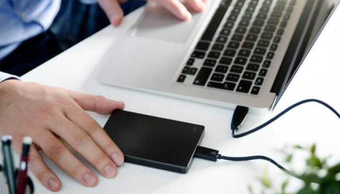 A person connecting a hard drive to a laptop improve your productivity.