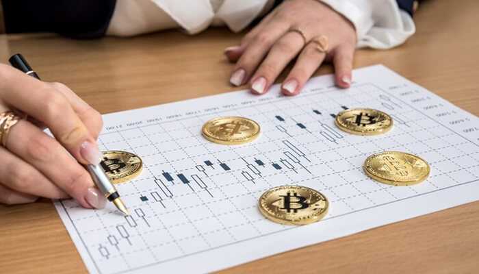 A person pointing a pen on a chart with bitcoins, that symbolizing bitcoin price analysis in trading