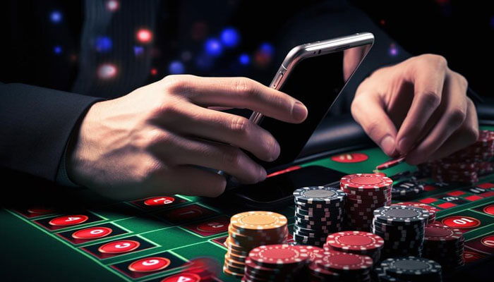 Person using a smartphone at a casino table with poker chips and a roulette layout, illustrating online gaming on the mcw casino app.