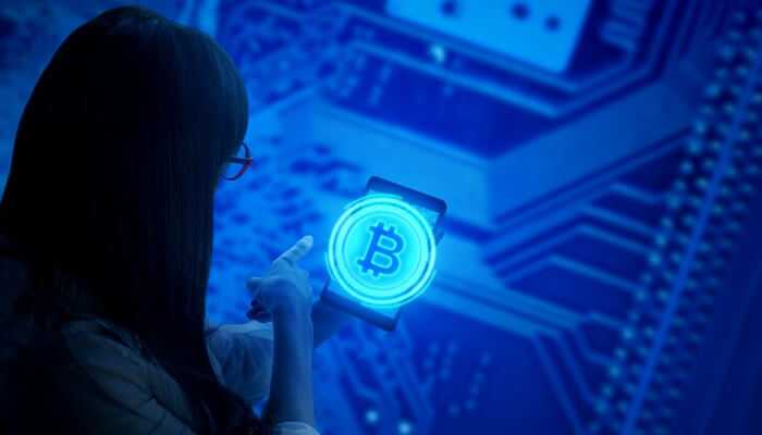 A woman pointing her fingure at a digital bitcoin symbol and with blue circuit background, represents bitcoin mining pool technology.