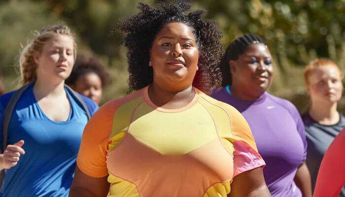 Group of plus-size women in bright athleisure wear participating in an outdoor fitness activity.