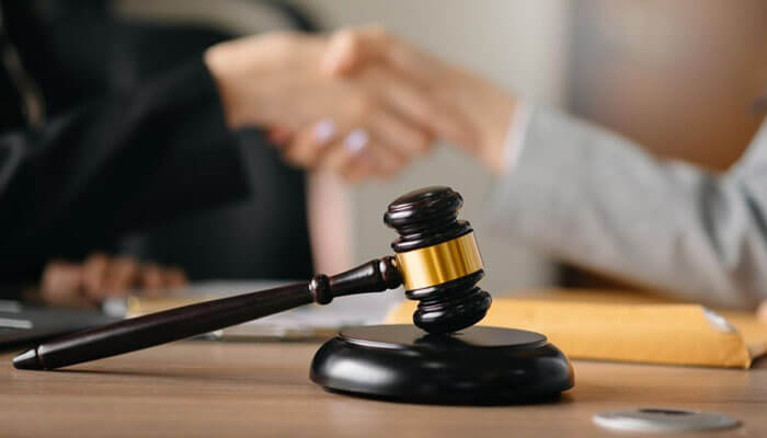 A handshake between a client and a personal injury lawyer, with a gavel in the foreground, indicating legal agreement or consultation.