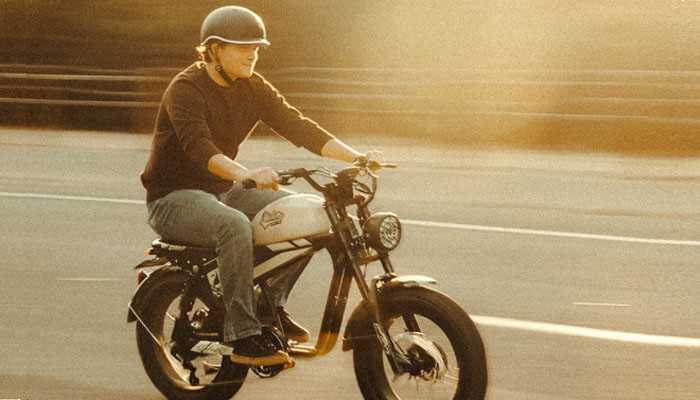 Man riding an electric bike on a city street during sunset, wearing a helmet, illustrating the convenience and style of urban commuting with eletric bikes