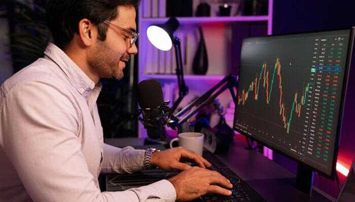 Trader analyzing financial market data on a monitor, engaged in copy trading to leverage insights from experienced investors and optimize portfolio performance