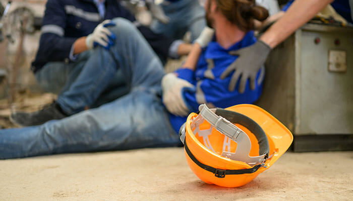 Construction worker injured on-site receiving assistance, with a safety helmet in the foreground, representing the losses construction workers may face after accidents