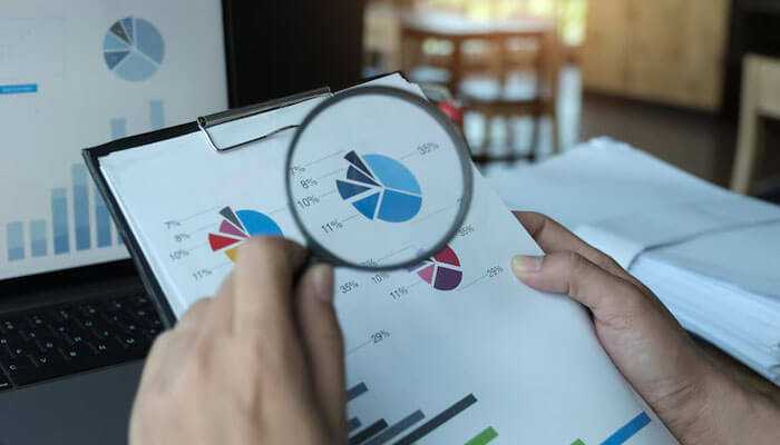 Analyzing market trends with charts and graphs under a magnifying glass, illustrating research and strategy in the secondary ticket market for ticket reselling