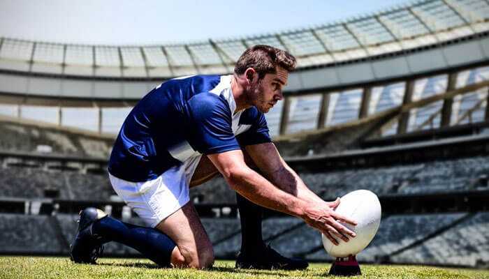 Rugby player in a stadium setting up the ball for a kick in an international sports tournaments.