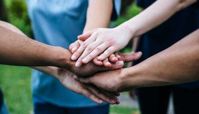 Group of people stacking their hands together in a gesture of teamwork and unity, symbolizing collaboration, trust, mutual support, and influencer marketing.