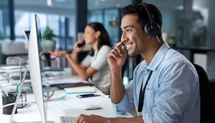 Customer service representatives using headsets and computers in a modern office, illustrating the implications of conversation analytics to enhance customer interactions and service quality