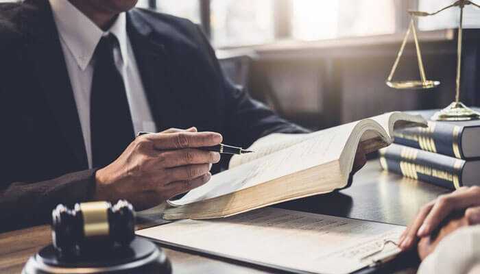 Professional consulting in a modern legal practice setting: legal books, gavel, and justice scales are on the desk.