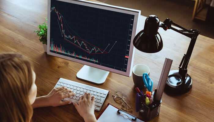 Person analyzing stock market trends on a computer screen with candlestick chart, exploring options for opening a demat account.