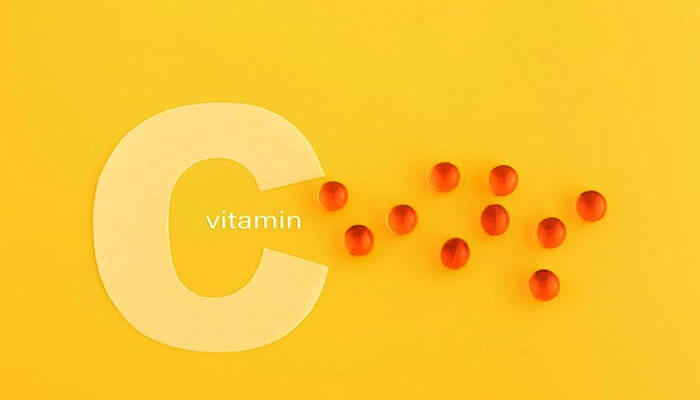 Orange pills near the large letter'C', representing vitamins to boost energy on yellow background.