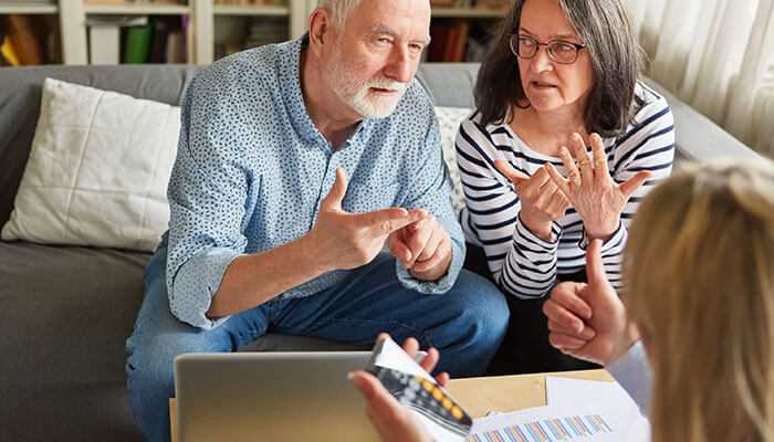 Senior couple saving for retirement, discussing financial strategies with a financial advisor, reviewing documents and calculations to secure a comfortable future