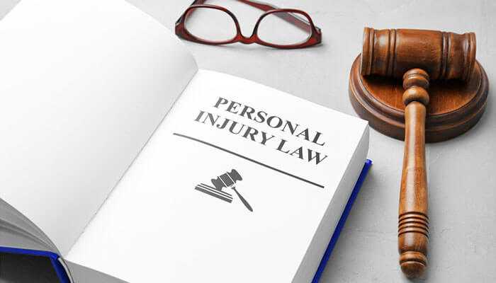 Open book titled personal injury law with a gavel and eyeglasses, symbolizing the connection between probate law and personal injury claims