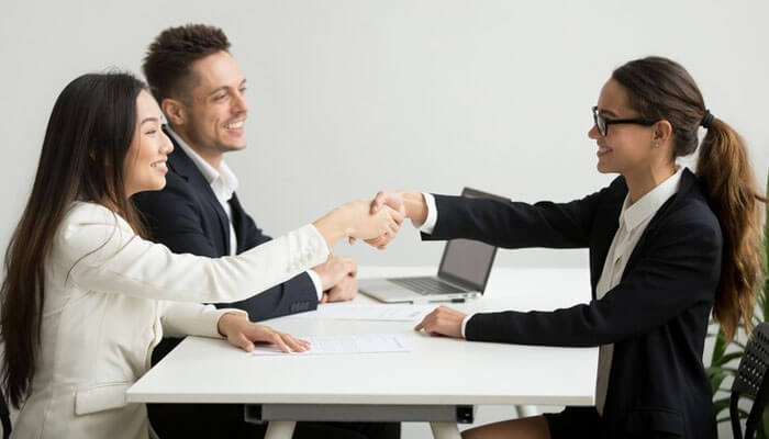 A handshake between professionals in a recruitment franchises setting, with a man and woman seated at the table