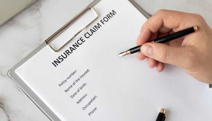 Pedestrian accident claim insurance claim form being filled out with a pen showing fields for policy number name of the insured date of birth address occupation and phone number