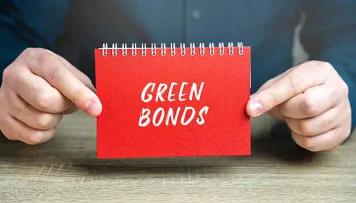 A person holding a red notepad with green bonds written, emphasizing concepts of sustainable investing.