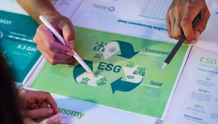 Close-up of hands reviewing an esg disclosure document with icons and a circular arrow, indicating collaboration or discussion