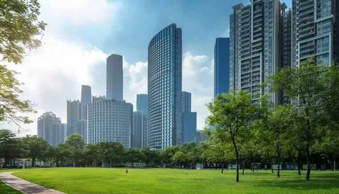 High-rise modern buildings beside a green park with a bright sky display the 2 bhk flats of mumbai.