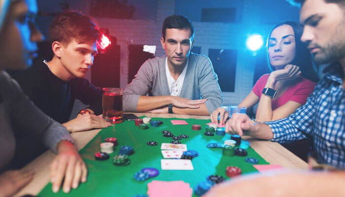 Group playing poker at green table with chips and cards, while showing awareness in online gambling safety.