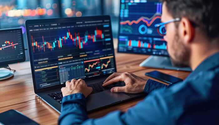 Person working on a laptop with stock market charts: workflow pains in financial services analysis.