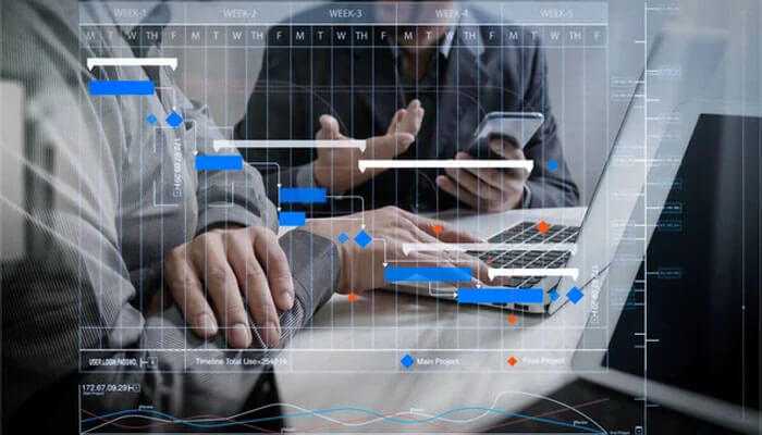 Team discussing complex project schedules on a digital interface; data analysis and project management highlighted.