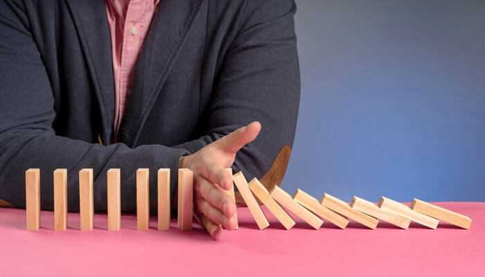 A person stops falling dominoes, symbolizing micro-investing as small actions that prevent financial instability