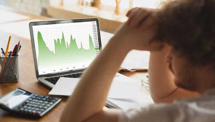 A person reviewing a green financial chart on a laptop, reflecting concepts of behavioral finance and decision-making.