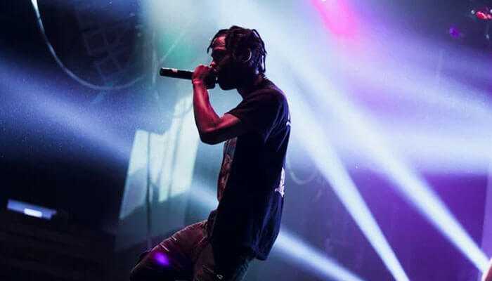 Travis scott net worth travis scott performing on stage under vibrant colorful lights showcasing his energetic presence during a live concert