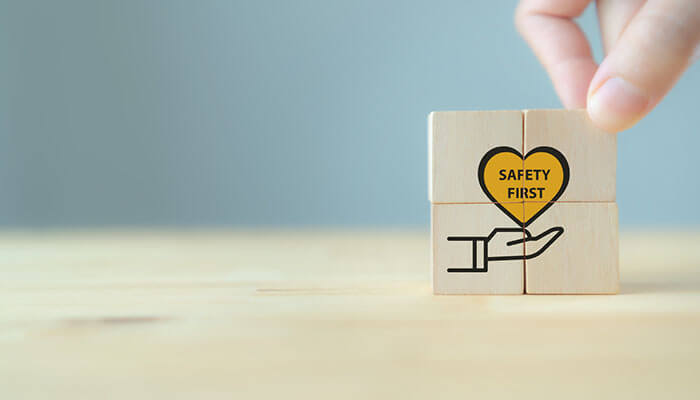 To avoid slips and falls in the workplace. The image depicts wooden blocks, one with a heart imprinted "safety first" on a hand, emphasizing safety as a core value.