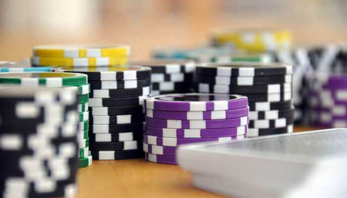 Stacks of colored poker chips and a deck of cards arranged on a table.