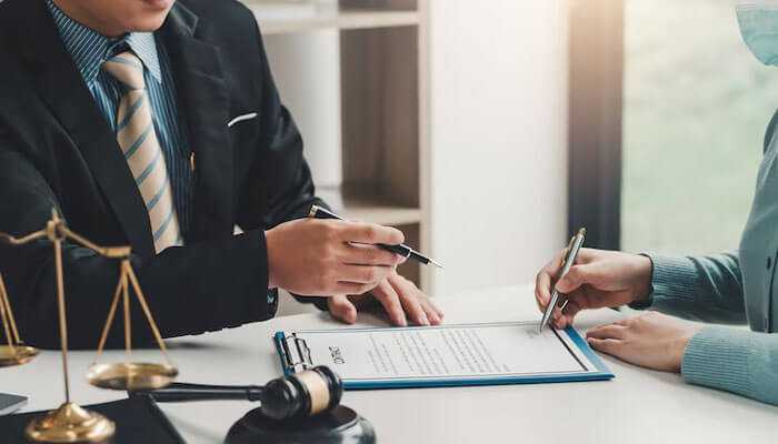 Employment lawyers in nyc reviewing a legal document with a client, alongside justice scales and a gavel.