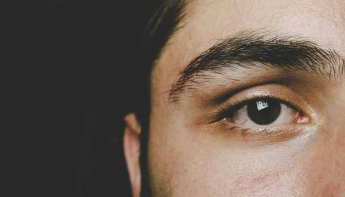 Close-up shot of the human eye: dark brown naturally colored iris and thick eyebrows, with things to consider before undergoing lasik in nyc.