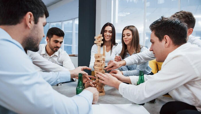 Team playing jenga during a team-building activity in the office, fostering collaboration and custom traditions in entrepreneurship.