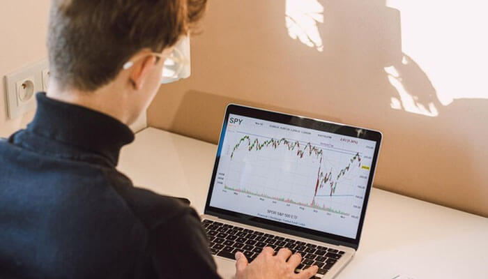 A person analyzing a stock market chart on a laptop screen, representing the growing trend of online trading in bangladesh and its financial opportunities