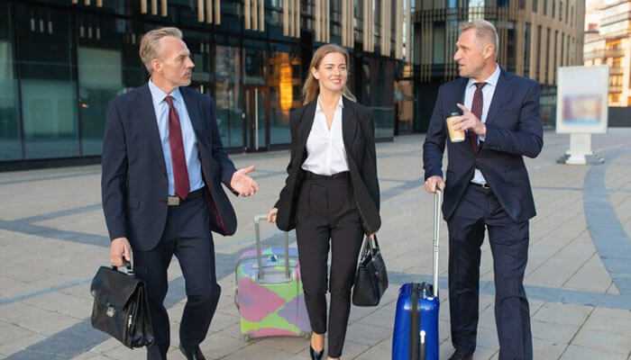 Business professionals with luggage discussing corporate travel management