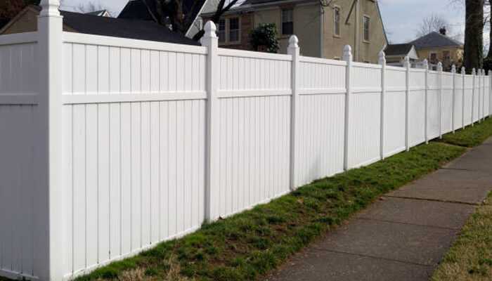 A white fence along a sidewalk, symbolizing the psychology of safety behind a fence and how physical barriers contribute to a sense of security and protection.