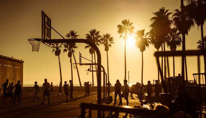 Streetball players on an outdoor court at sunset, showcasing skills that influenced nba playing styles