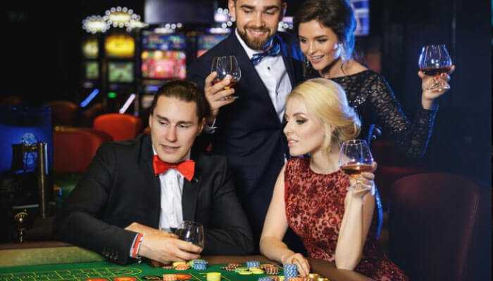 Elegant people in formal attire enjoying drinks and playing at a casino table, offering advice for casino enthusiasts.