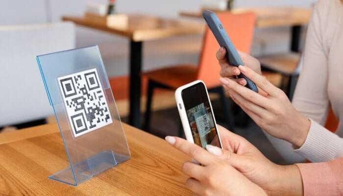 Entrepreneurs using smartphones to scan a qr code on a table stand in a modern cafe, highlighting entrepreneurial success with qr codes.