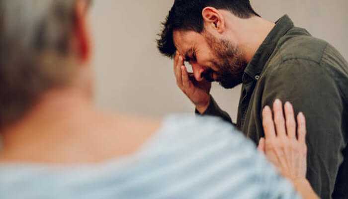 A distressed man receiving emotional support during a counseling session, highlighting the importance of compassionate care in Alcoholic Rehab.

