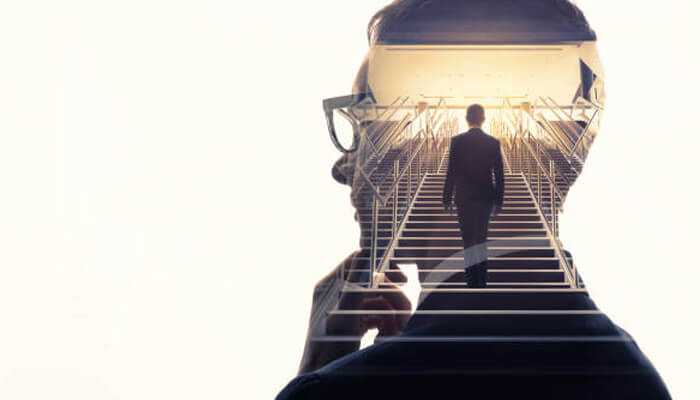 Double exposure image of carlos alexandre rozwadowski’s silhouette overlaid with a man walking up a staircase toward a bright light, symbolizing progress.