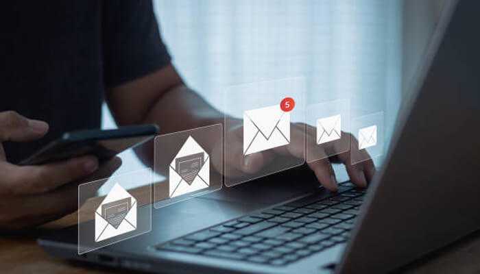 A user managing multiple email notifications on a laptop and smartphone, showcasing streamlined communication through cdp solutions.