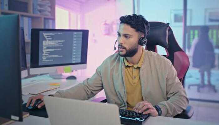 Call center agent using data analytics in call centers to provide customer support while working with dual monitors and a headset.