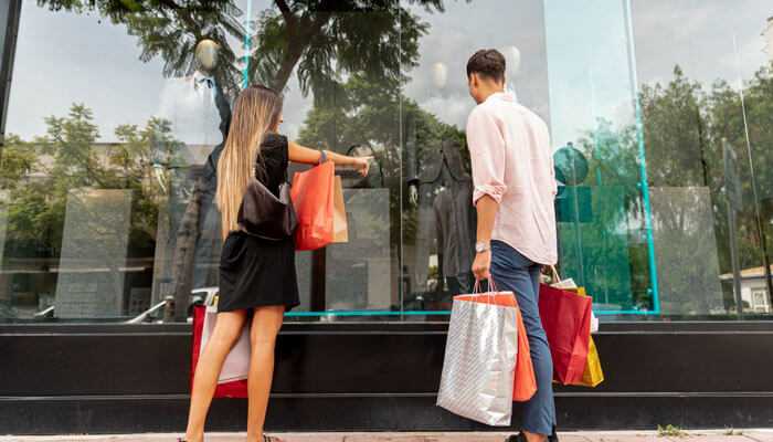 Shoppers standing in front of a neat and tidy storefront with large glass windows, showcasing a clean and organized display inside.