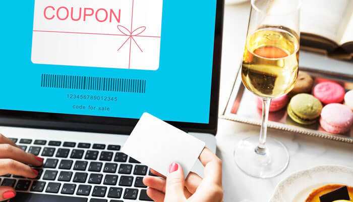 User applying gc coupons during online checkout on a laptop, with wine and macarons in the background for a cozy shopping experience.