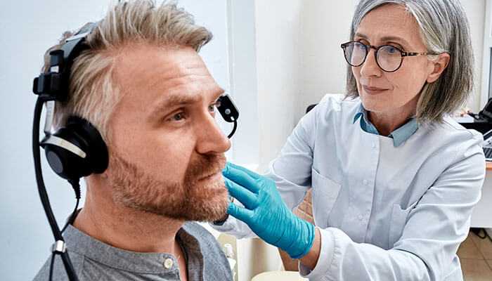 Healthcare professional performing a hearing test to detect occupational diseases like workplace-related hearing loss.