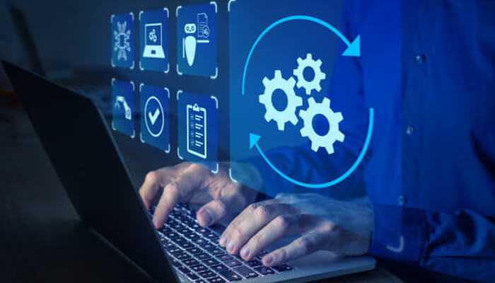 Hands typing on a laptop with automation icons, representing as400 job scheduling automation and operational efficiency in ibm i systems.