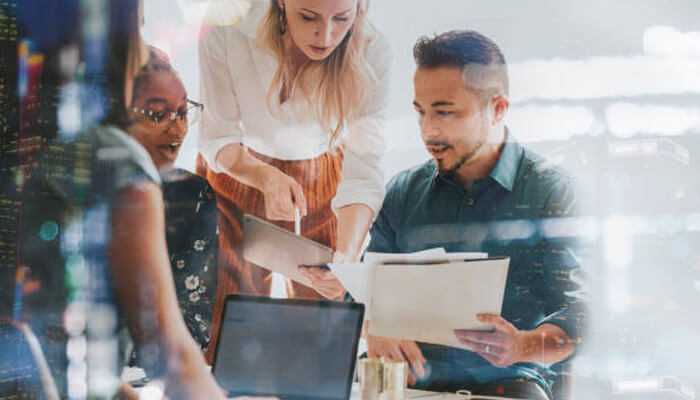 Business team collaborating in a modern office, analyzing documents and data, symbolizing the real-world application of ai automation in enterprise workflows.