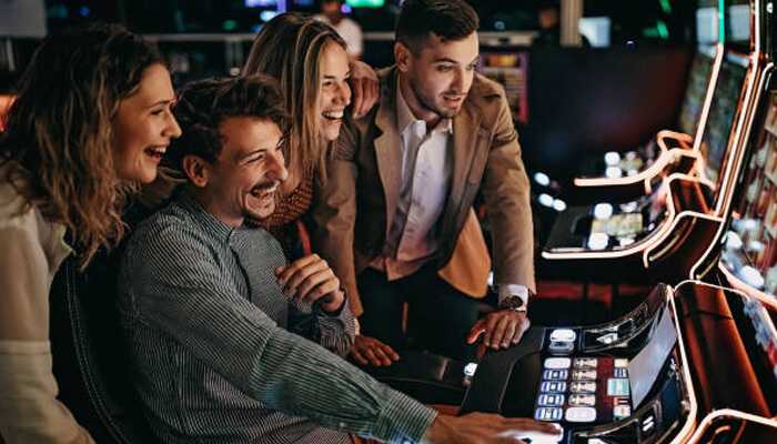 A group of friends enjoying one of the four fun games to play with friends at a lively casino, sharing laughs around a slot machine.